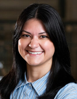 A woman with long dark hair waring a striped blue button-down.