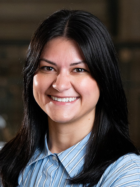 A woman with long dark hair waring a striped blue button-down.