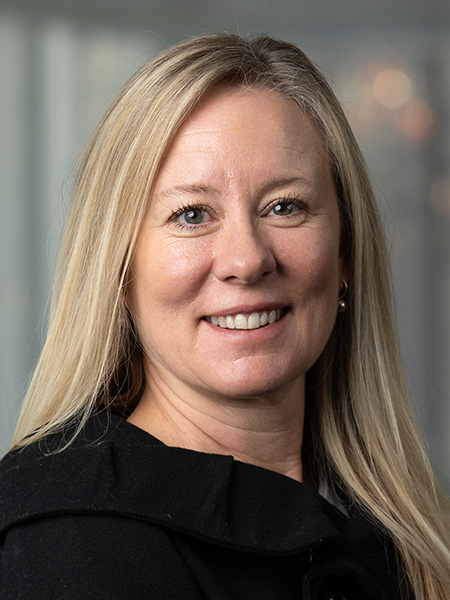 A white woman with long blonde hair waring a dark jacket.