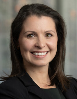 A French woman with shoulder length dark hair wearing a black blazer.