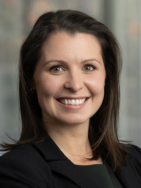 A French woman with shoulder length dark hair wearing a black blazer.