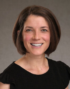White woman with brown hair cut in a bob wearing a dark blouse.