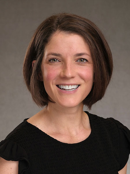 A white woman with brown hair cut in a bob wearing a dark blouse.