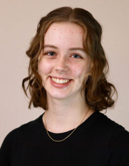 A woman with wavy shoulder length hair wearing a black shirt