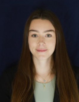 A white woman with long brown hair wearing a dark blazer.