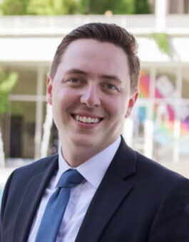 A white man with short brown hair wearing a suit and tie.