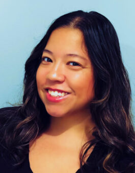 a woman with long dark hair wearing a black blouse.