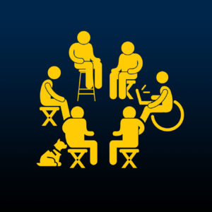 6 people sit in a circle on various chairs and assistive devices. 1 person has a service dog and another holds a laptop.